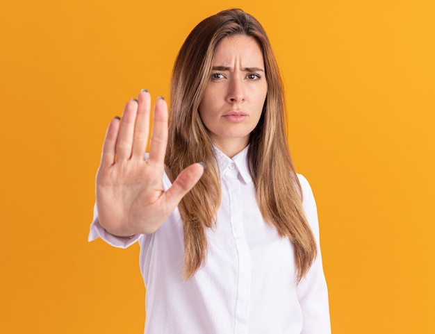 Serious young pretty caucasian girl gestures stop sign