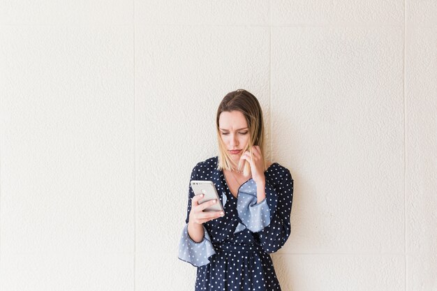 Serious young woman holding cellphone