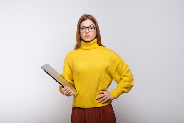 Serious young woman holding laptop