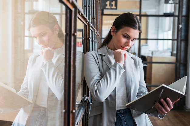 Serious young woman looking at diary at office