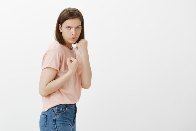 Serious young woman ready to fight, raising clenched fists
