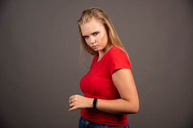 검은 벽에 빨간 셔츠에 심각한 젊은 여자.
