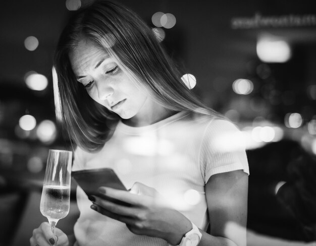 Serious young woman using a smartphone at a rooftop bar in the e