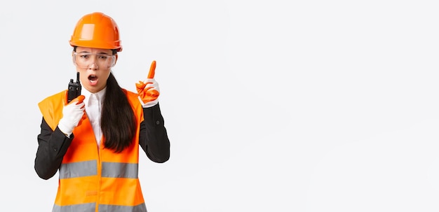 Seriouslooking asian female industrial engineer technician in safety helmet and uniform command cons