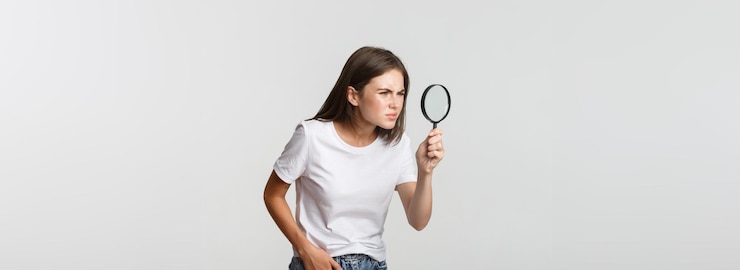 無料Photo 白い虫眼鏡を通して何かを探している深刻な魅力的な若い女性