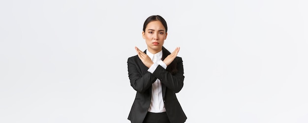 Free photo seriouslooking confident businesswoman in black suit showing cross gesture to forbid action restrict forbid or prohibit making any deals stop working with client white background time out