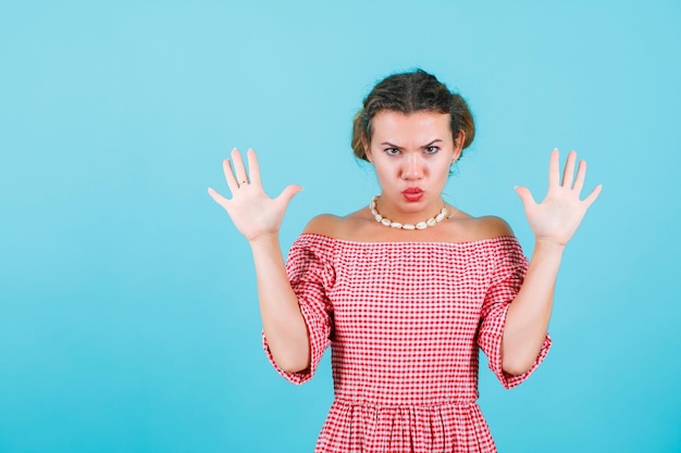 Free photo seriously and angry girl is raising up and opening wide her handfuls on blue background