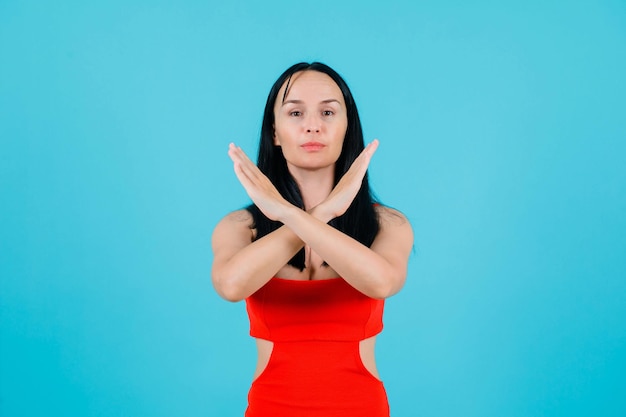 Seriously girl is crossinh her hands on blue background