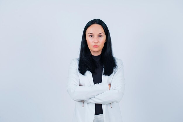 Seriously girl is looking at camera by crossing arms on white background