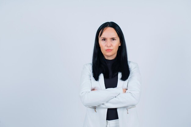 Seriously girl is looking at camera by crossing arms on white background