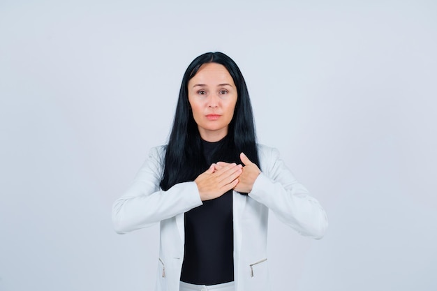 Seriously girl is looking at camera by putting hands on chest on white background