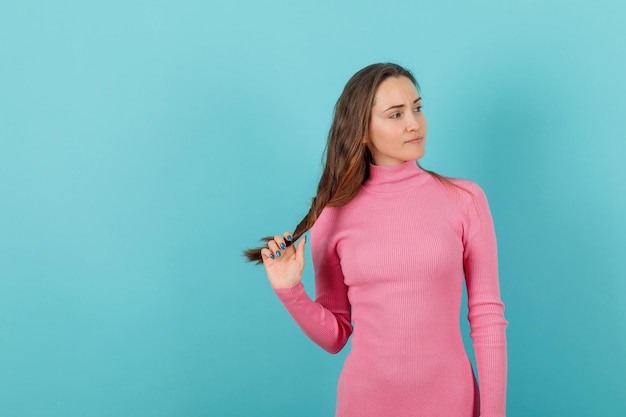 Seriously girl is looking right by holding hair on blue background