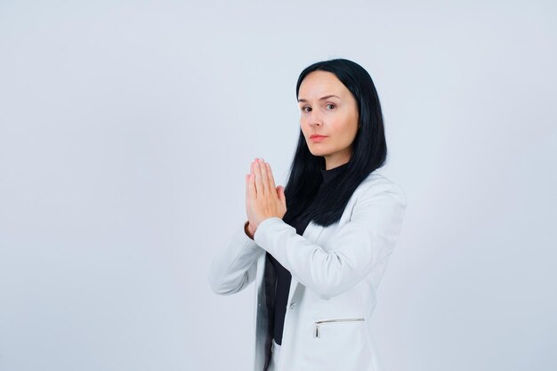 Seriously girl is praying by holding hands together on white background