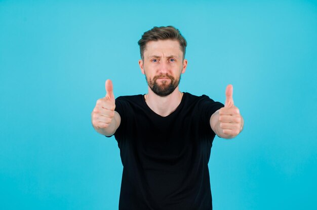 Seriously man is looking at camera by showing perfect gestures on blue background