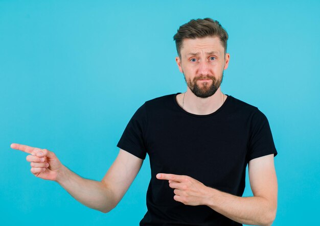 Seriously man is pointing left with forefingers on blue background