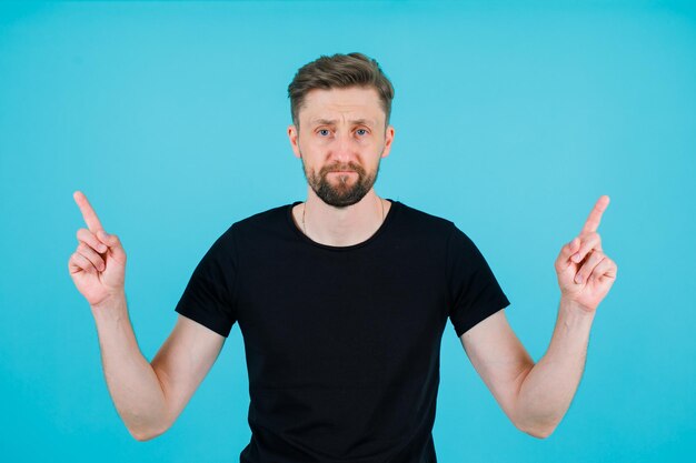 Seriously man is pointing up with forefinger on blue background