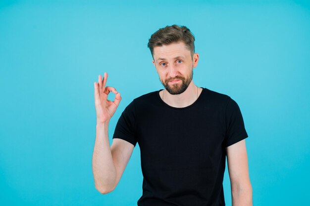 Seriously man is showing okay gesture with hand on blue background