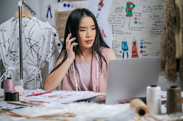 Seriously Young designer talking with smartphone while use laptop computer to checking together