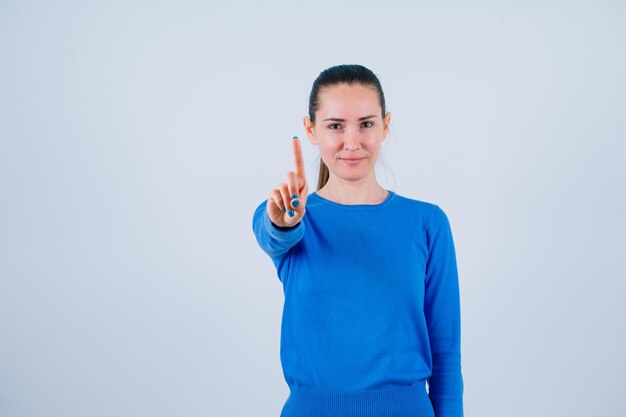 Seriously young girl is showing a minute gesture on white background