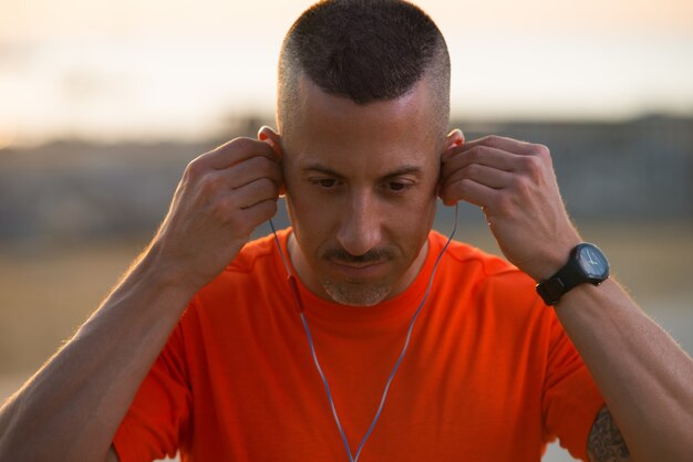 Serous mid adult male athlete putting on earphones