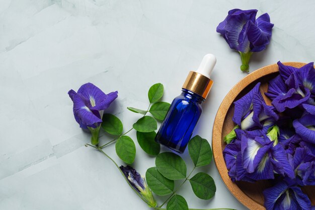 Serum bottle of Butterfly Pea Flower oil put on white marble background