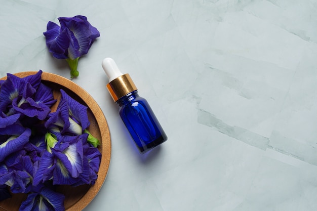 Serum bottle of Butterfly Pea Flower oil put on white marble background