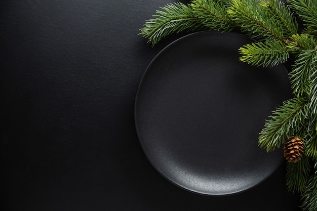 어두운 색조의 크리스마스 테이블 설정을 제공합니다. 어두운 배경에 어두운 접시