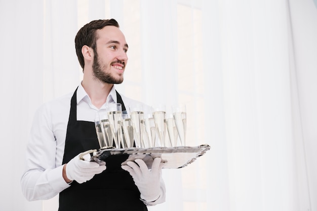 Free photo server holding tray with champagne glasses