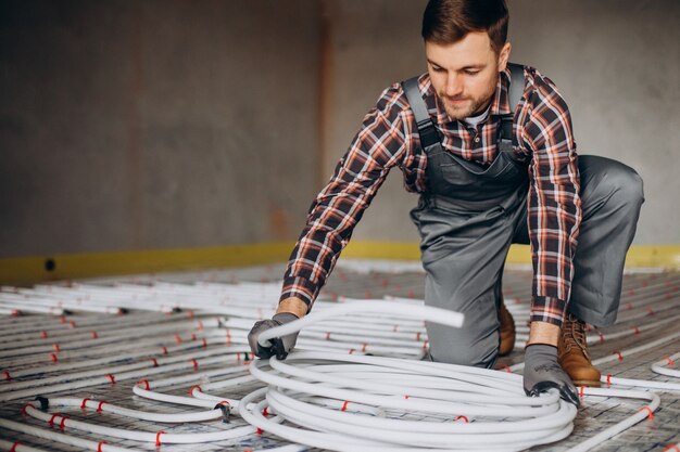 Service man instelling house heating system under the floor