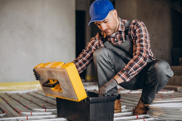 Service man instelling house heating system under the floor