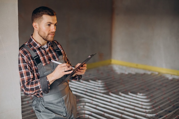 Service man instelling house heating system under the floor