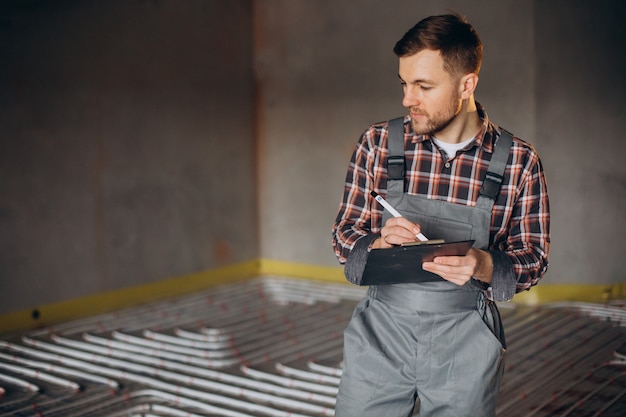 Service man instelling house heating system under the floor