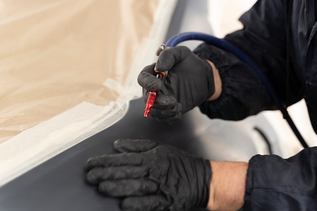 Service worker painting car in auto service