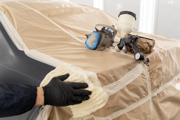 Service worker painting car in auto service