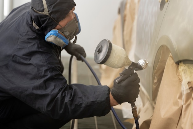 Free photo service worker painting car in auto service