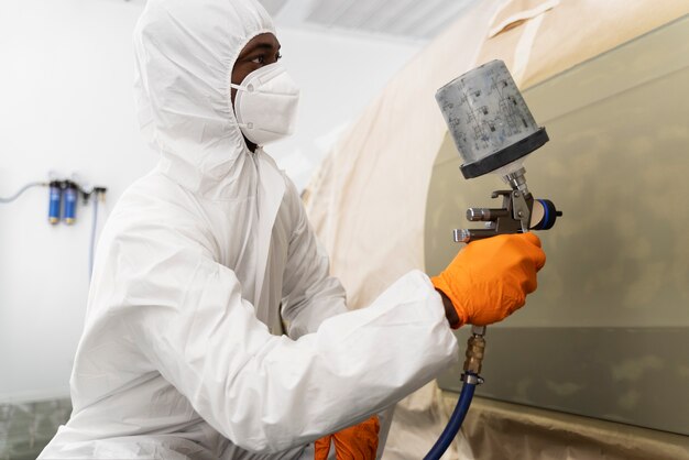 Service worker painting car in auto service