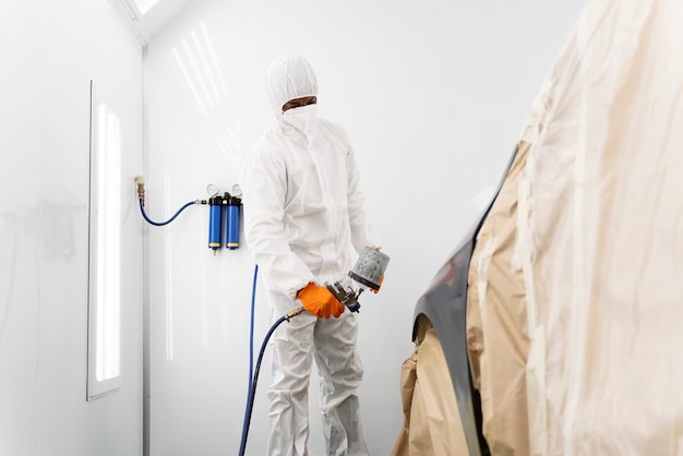 Service worker painting car in auto service