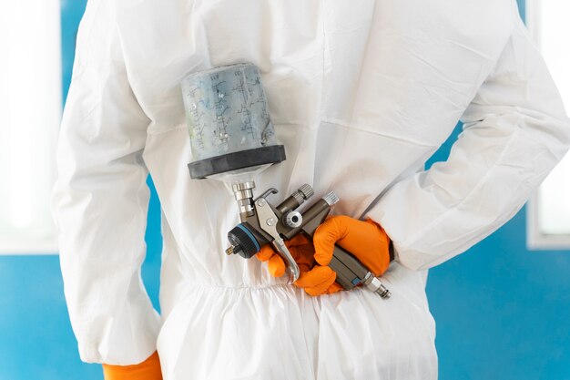 Service worker painting car in auto service