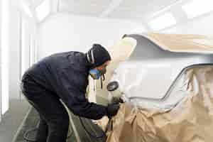 Free photo service worker painting car in auto service