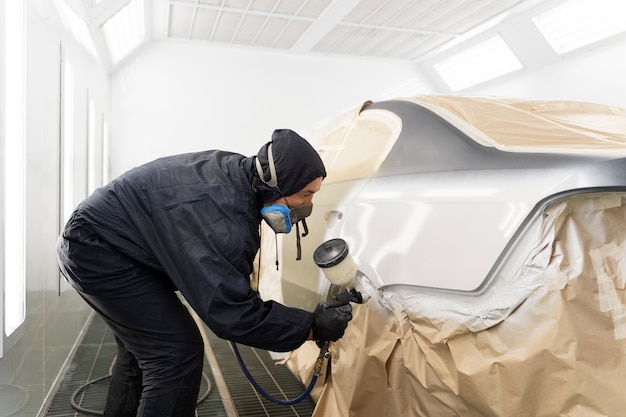 Service worker painting car in auto service