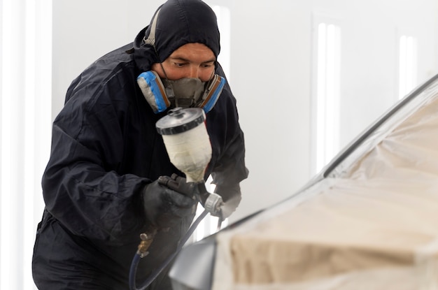 Service worker painting car in auto service