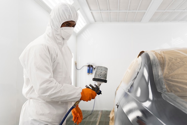 Free photo service worker painting car in auto service