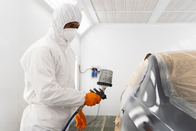 Service worker painting car in auto service