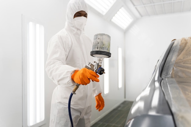 Service worker painting car in auto service