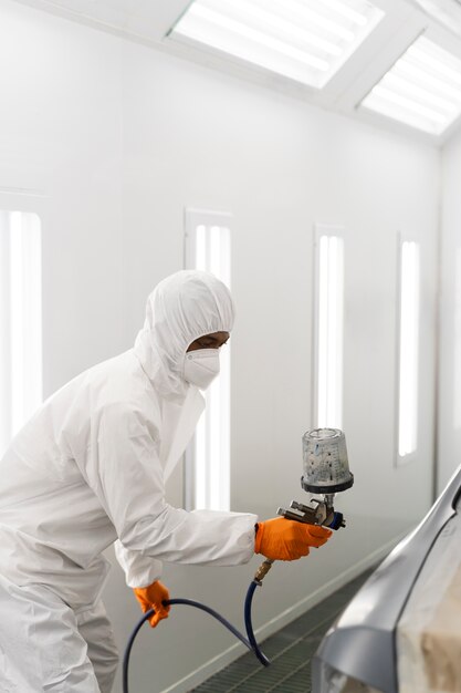 Service worker painting car in auto service