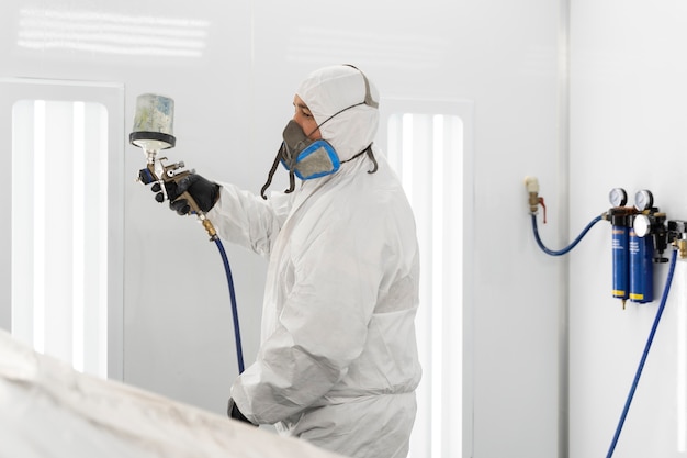 Service worker painting car in auto service