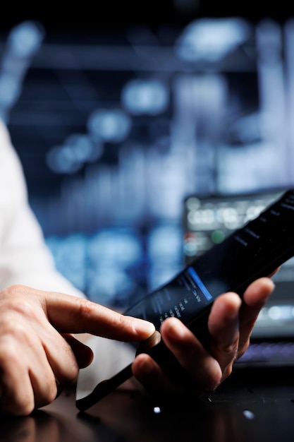 Serviceman coding in high tech data center using javascript language, close up. Meticulous repairman updating software on server rigs on tablet terminal, ensuring optimal performance and security