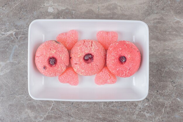 Serving of cookies and jelly sweets on a platter on marble surface