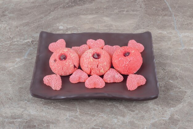 Serving of cookies and jelly sweets on a platter on marble surface