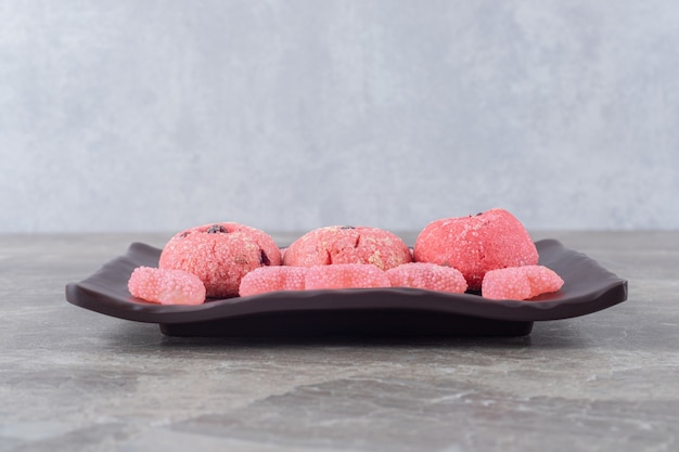 Serving of cookies and jelly sweets on a platter on marble surface